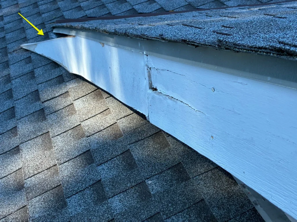 Loose apron flashing and exposed fasteners along the roof-to-wall connection requiring repair.