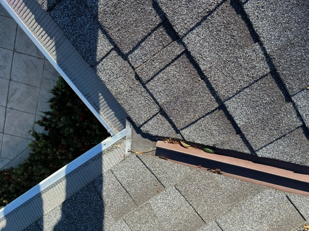 Visible gap beneath the roof edge flashing at an eave corner requiring corrective roofing work.
