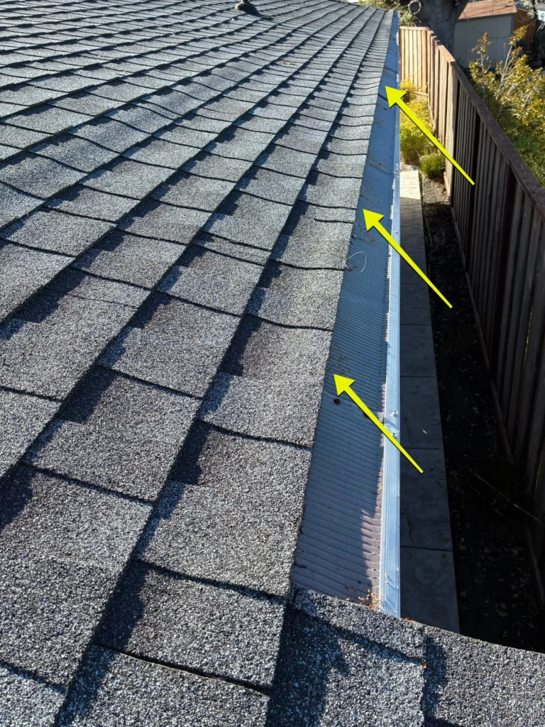 Exposed nail penetration and debris in metal roof valley flashing identified as potential leak sources.